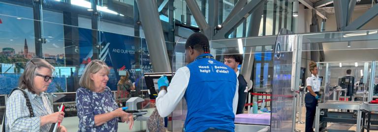 CATSA Facilitator assisting a passenger through airport screening.