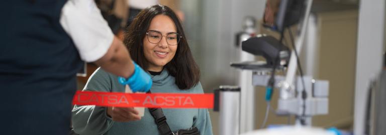 A passenger in a wheelchair is handing their paper boarding pass to a screening officer.
