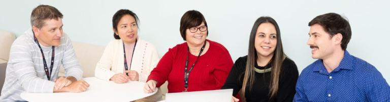 A group of CATSA procurement and contracting employees sitting and speaking in a common area. 