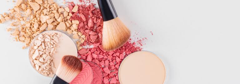 Makeup brushes and powders on a white table. 