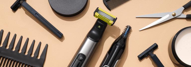 Various razors, combs, and scissors laying on a beige background.