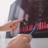Selective focus of data analysts pointing on graphs on computer monitor