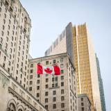 Old and new buildings seen from the ground with a Canadian flag waiving.